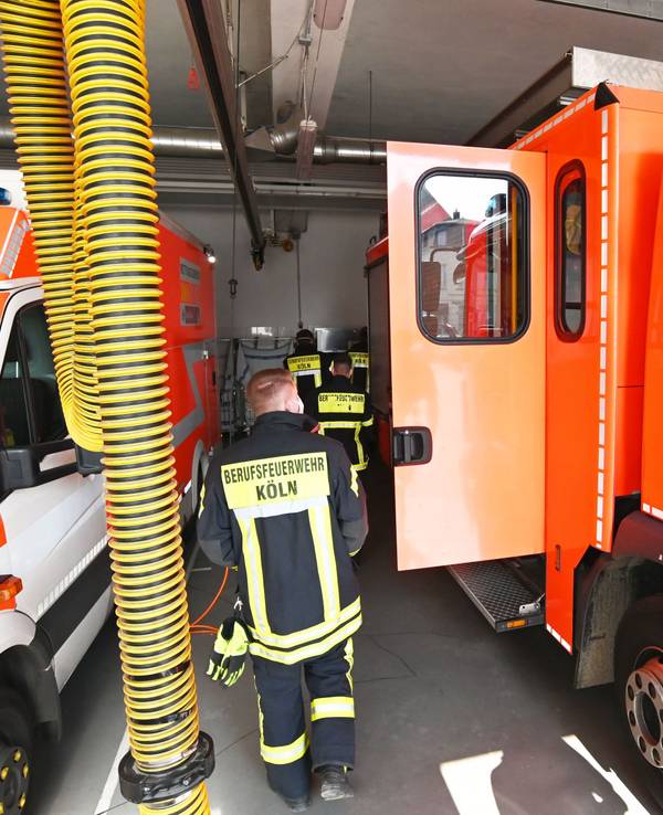 Einsatzkräfte der Feuerwehr Köln laufen an Einsatzfahrzeugen vorbei.