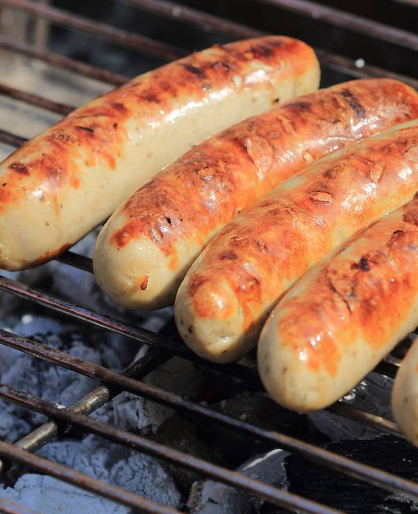 Bratwürste liegen auf einem Holzkohle-Grill.