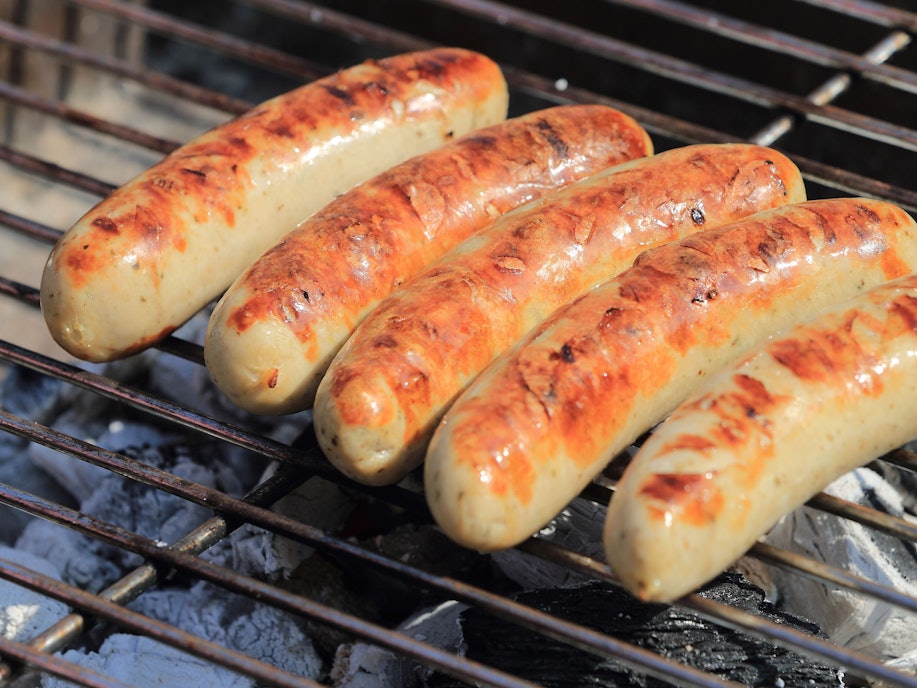 Bratwürste liegen auf einem Holzkohle-Grill.