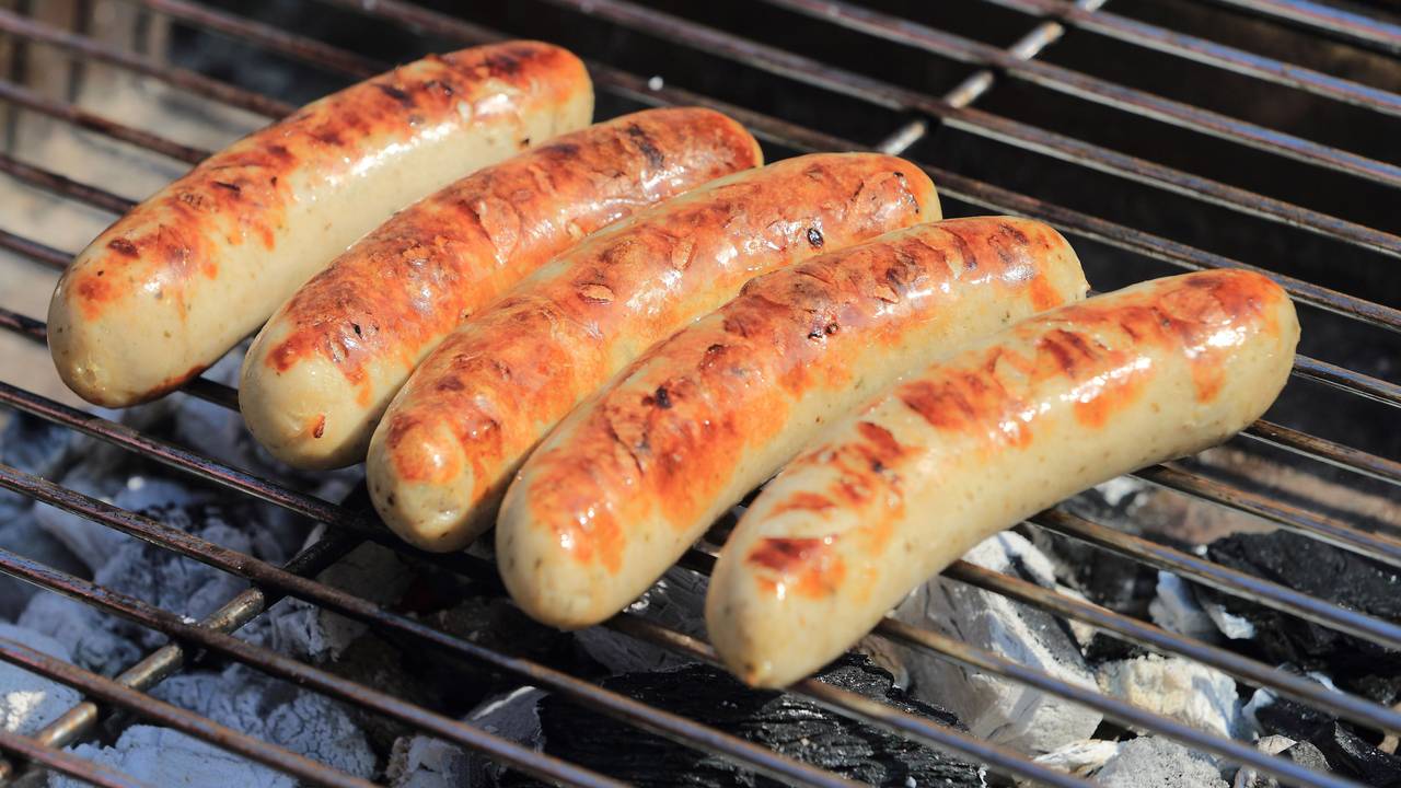Bratwürste liegen auf einem Holzkohle-Grill.