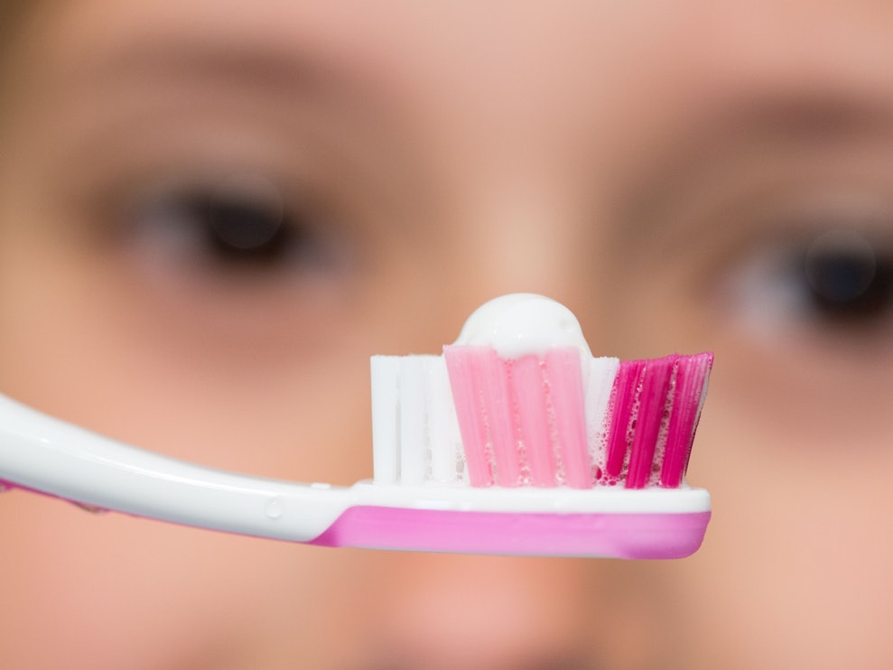 Eine Achtjährige schaut ihre Zahnbürste mit Zahnpasta an.