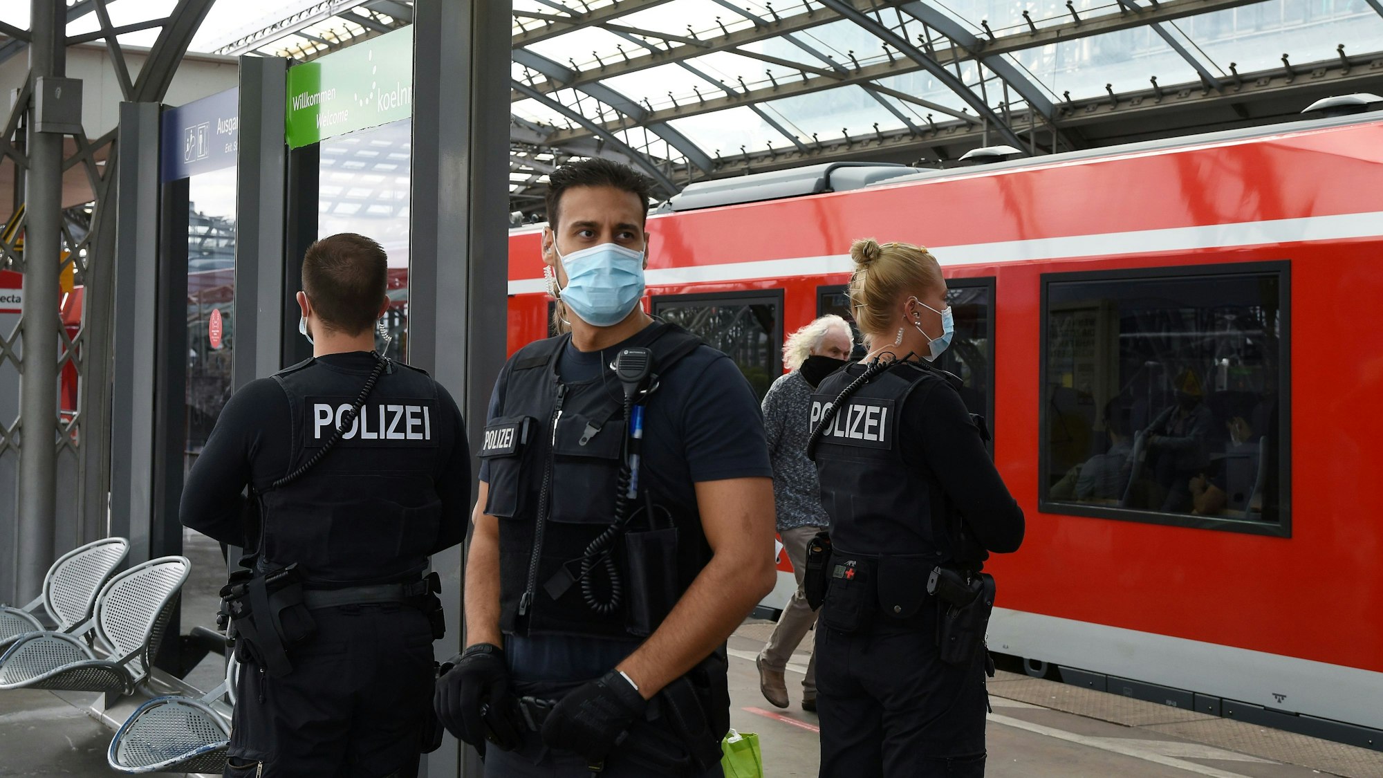 Eine Bundespolizistin und zwei Kollegen stehen auf einem Gleis im Kölner Hauptbahnhof.