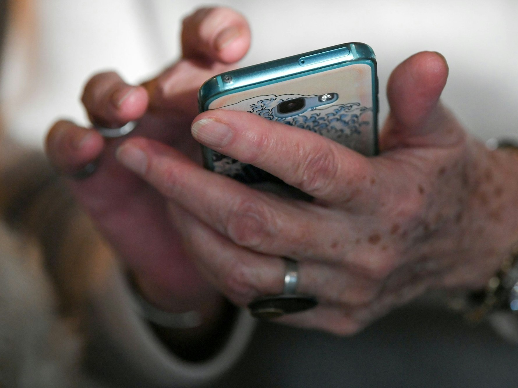 Eine Seniorin hält ihr Smartphone in den Händen.