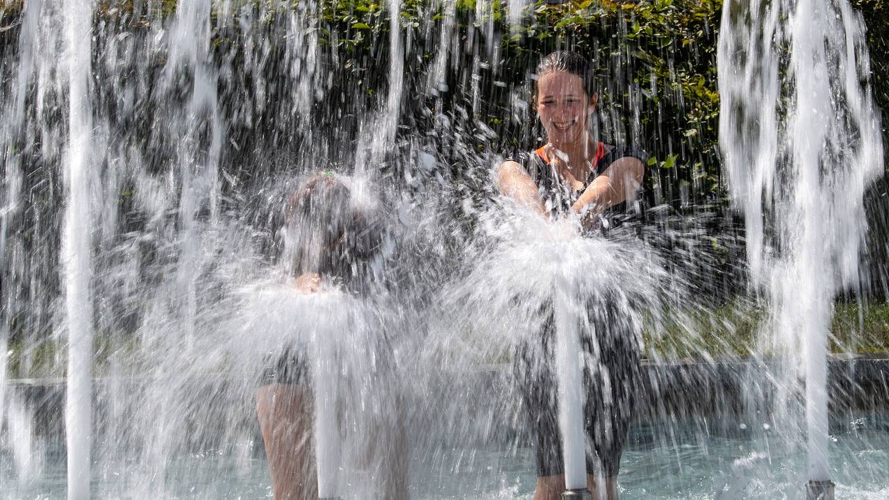 Menschen kühlen sich an den Fontänen im Stadtbrunnen auf dem Ulrichsplatz ab.
