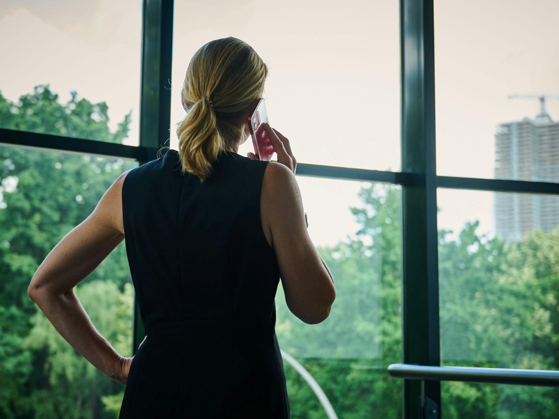Eine Frau steht in einem Bürozimmer am Fenster und telefoniert.