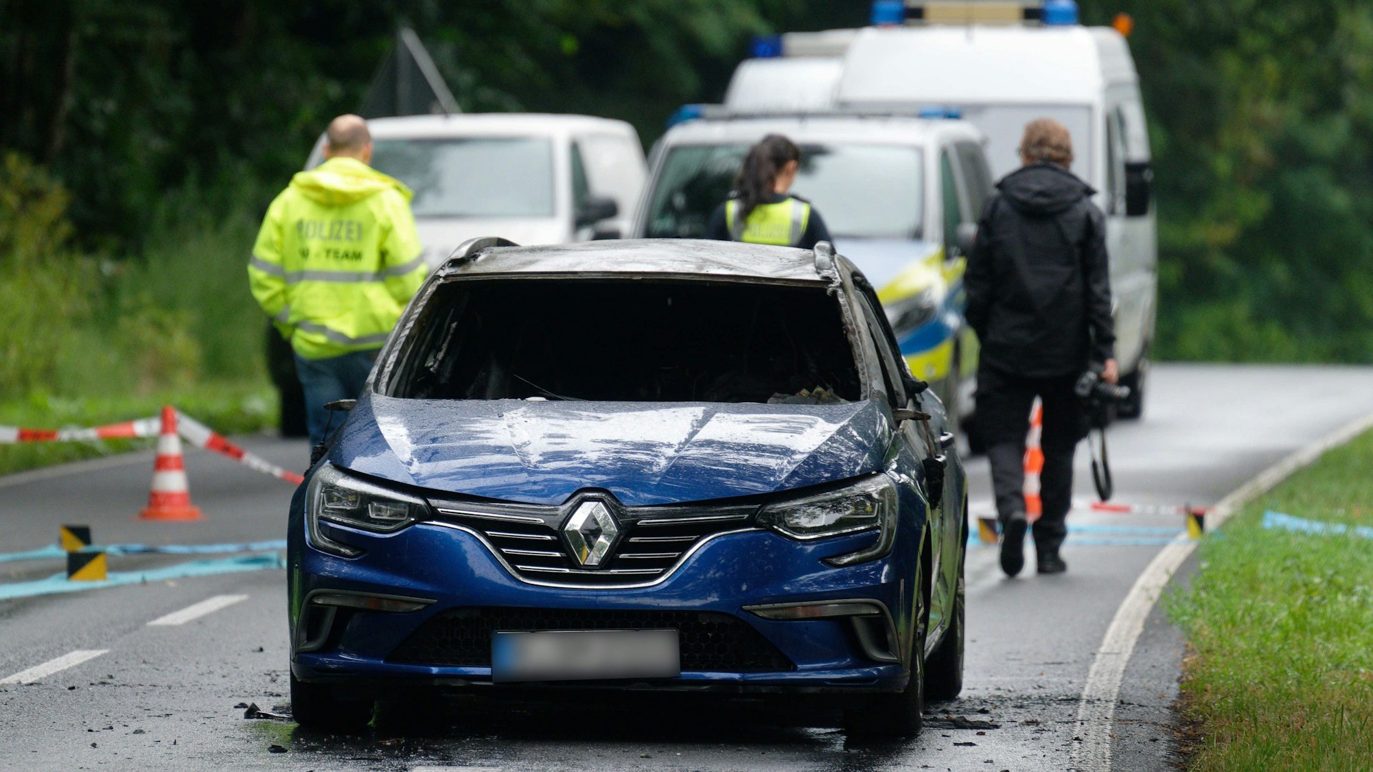 Ein ausgebranntes Auto steht nach einem Überfall auf einen Geldtransport am Tatort.