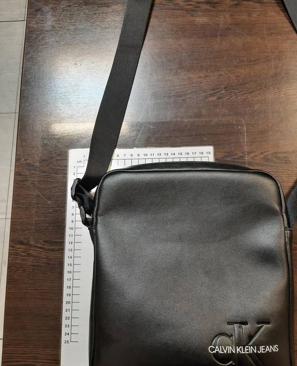 Eine schwarze Ledertasche liegt neben einem Maßband.
