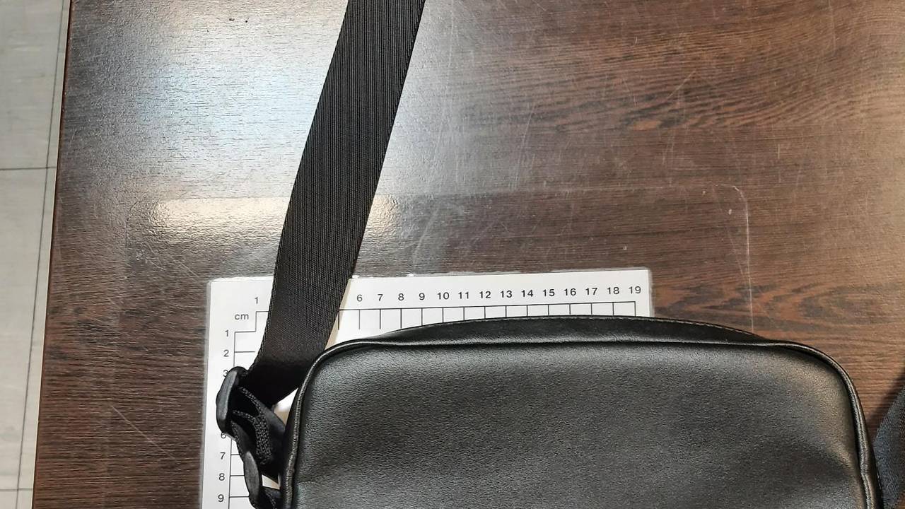 Eine schwarze Ledertasche liegt neben einem Maßband.