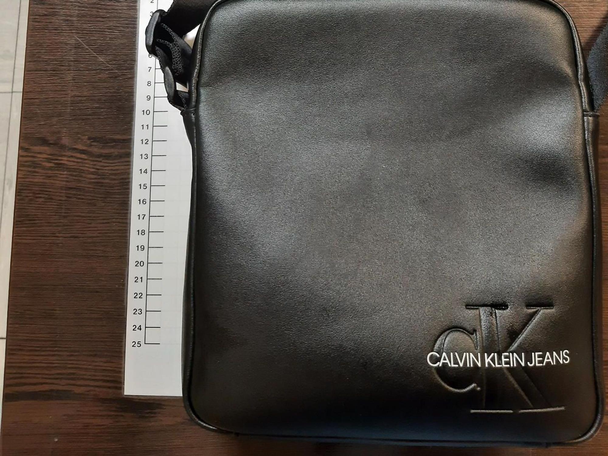 Eine schwarze Ledertasche liegt neben einem Maßband.