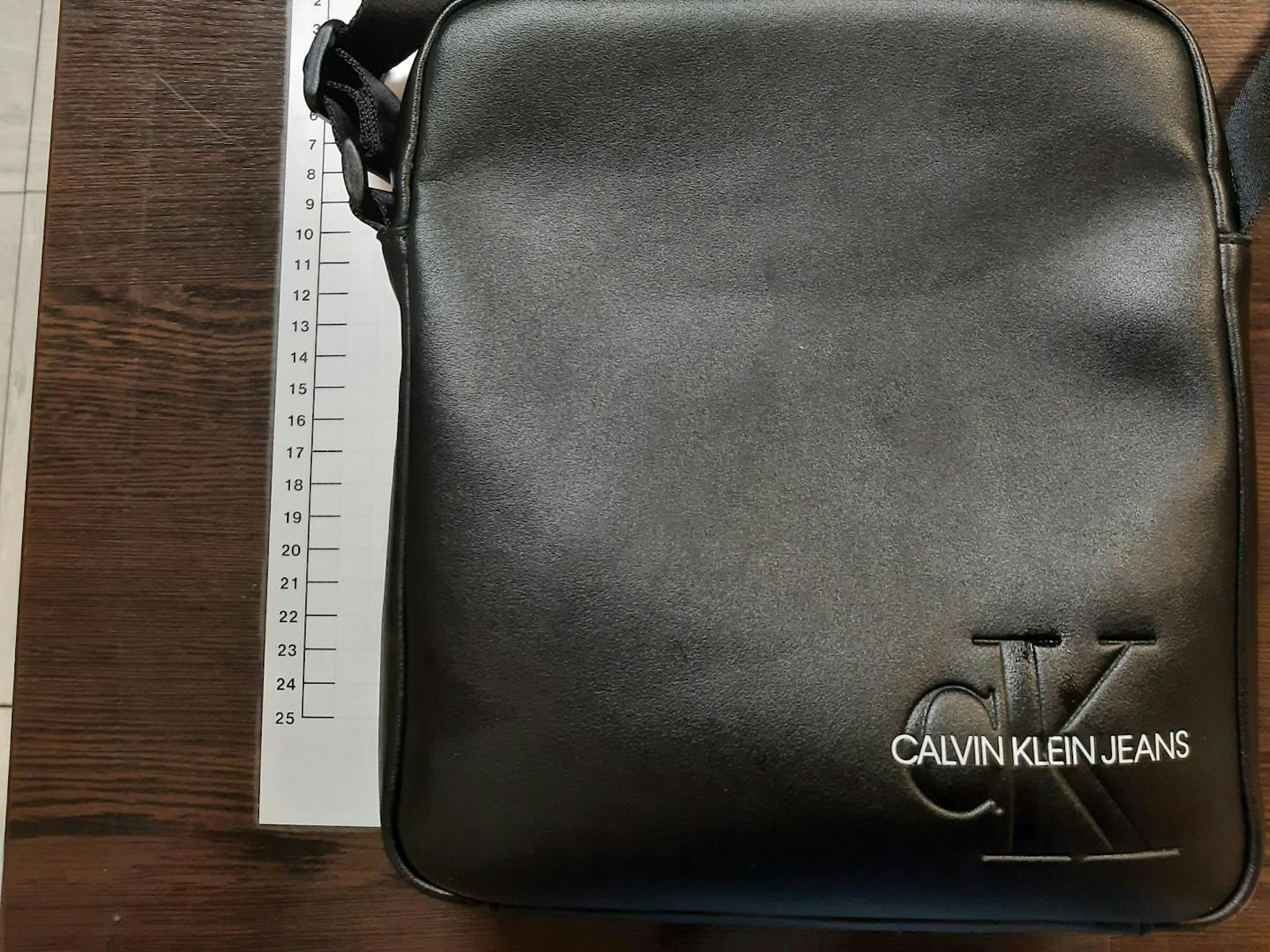 Eine schwarze Ledertasche liegt neben einem Maßband.