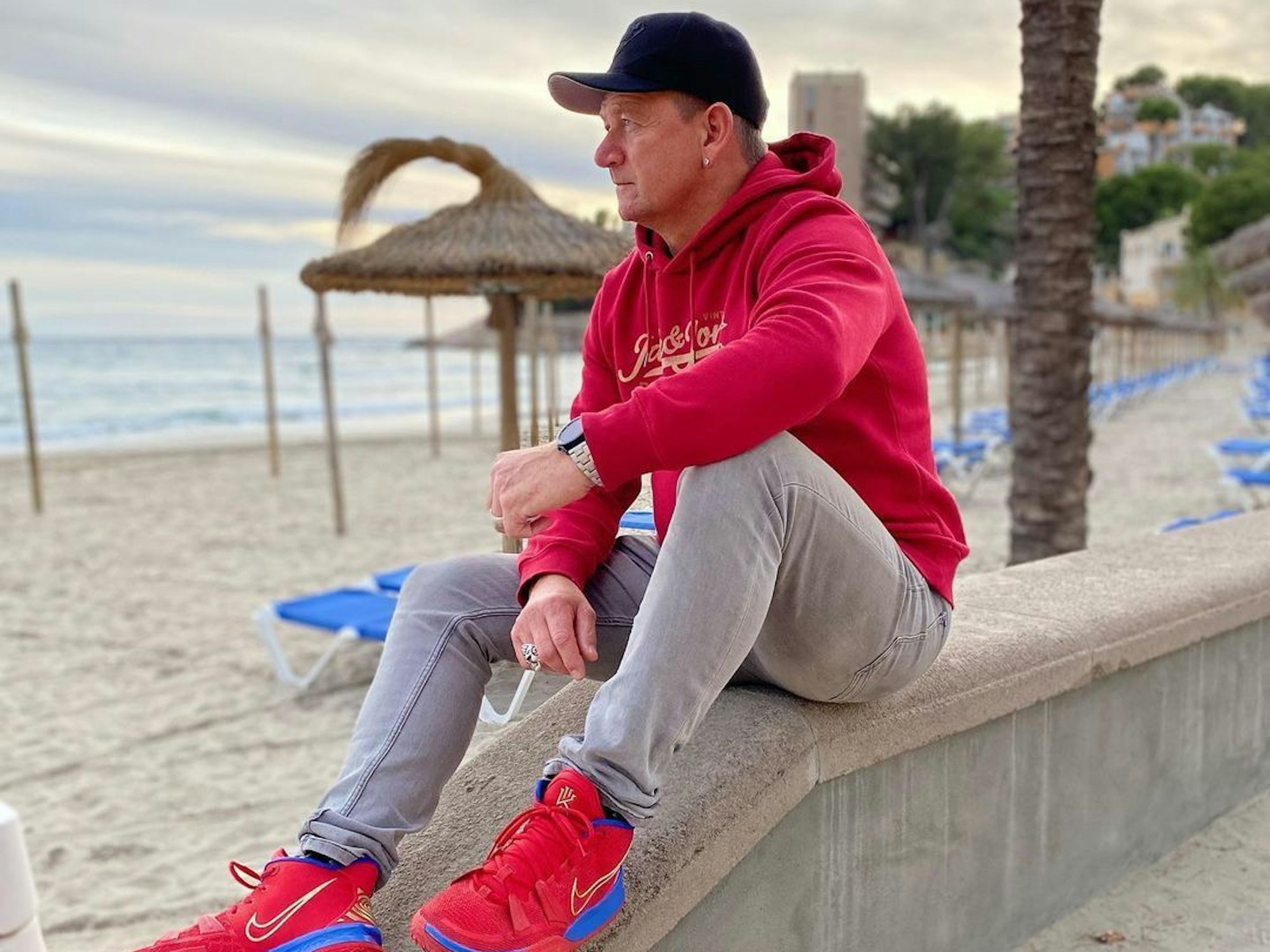 Der verstorbene Mallorca-Sänger Alex Zapata sitzt auf einem Mäuerchen am Strand .Das Foto postete er im April 2021 auf seinem Instagram-Profil.