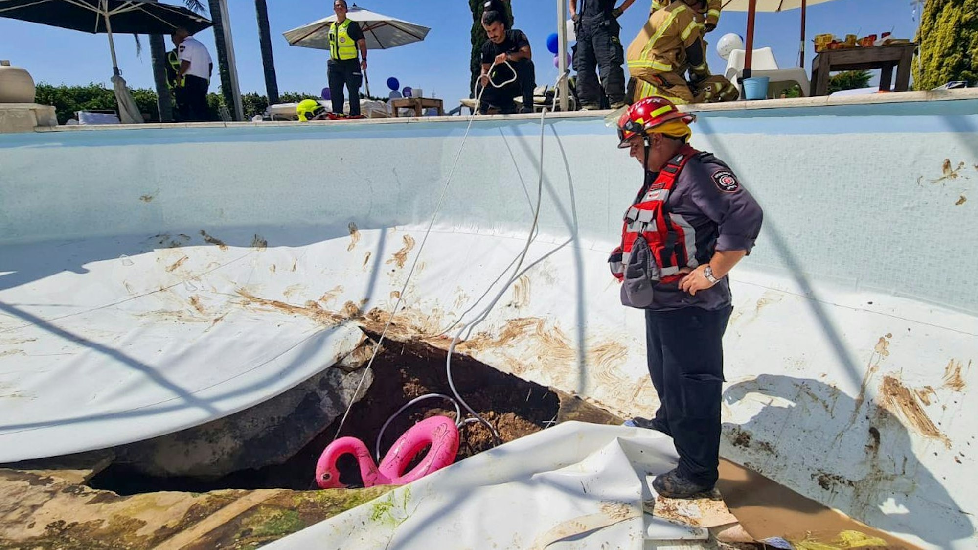 Einsatzkräfte stehen um das Loch im Pool in Israel.
