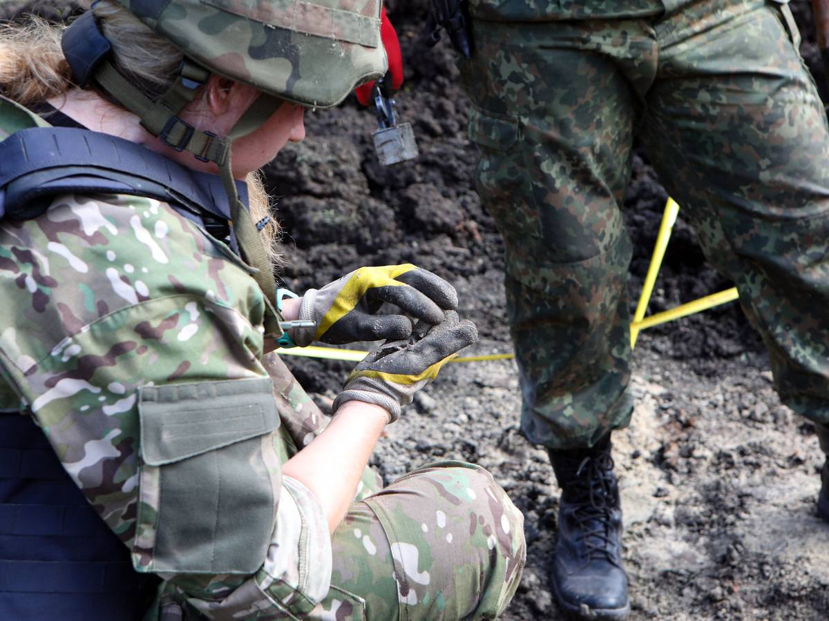 Eine Polizistin sucht nach den Splittern einer russischen Granate, die auf dem Gelände einer akademischen Einrichtung im Nordosten der Ukraine eingeschlagen ist.