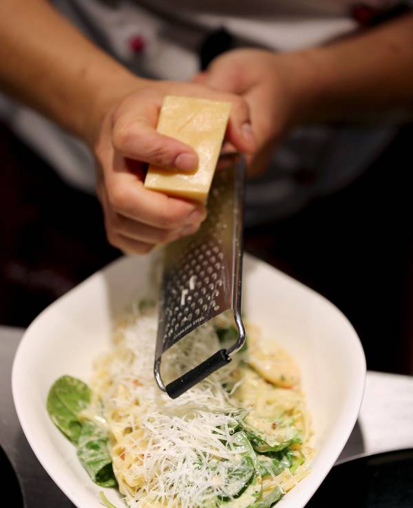 Ein Köchin reibt in einer Filiale der Restaurantkette Vapiano Parmesan auf ein Pasta-Gericht.