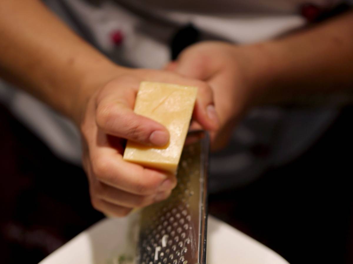 Ein Köchin reibt in einer Filiale der Restaurantkette Vapiano Parmesan auf ein Pasta-Gericht.