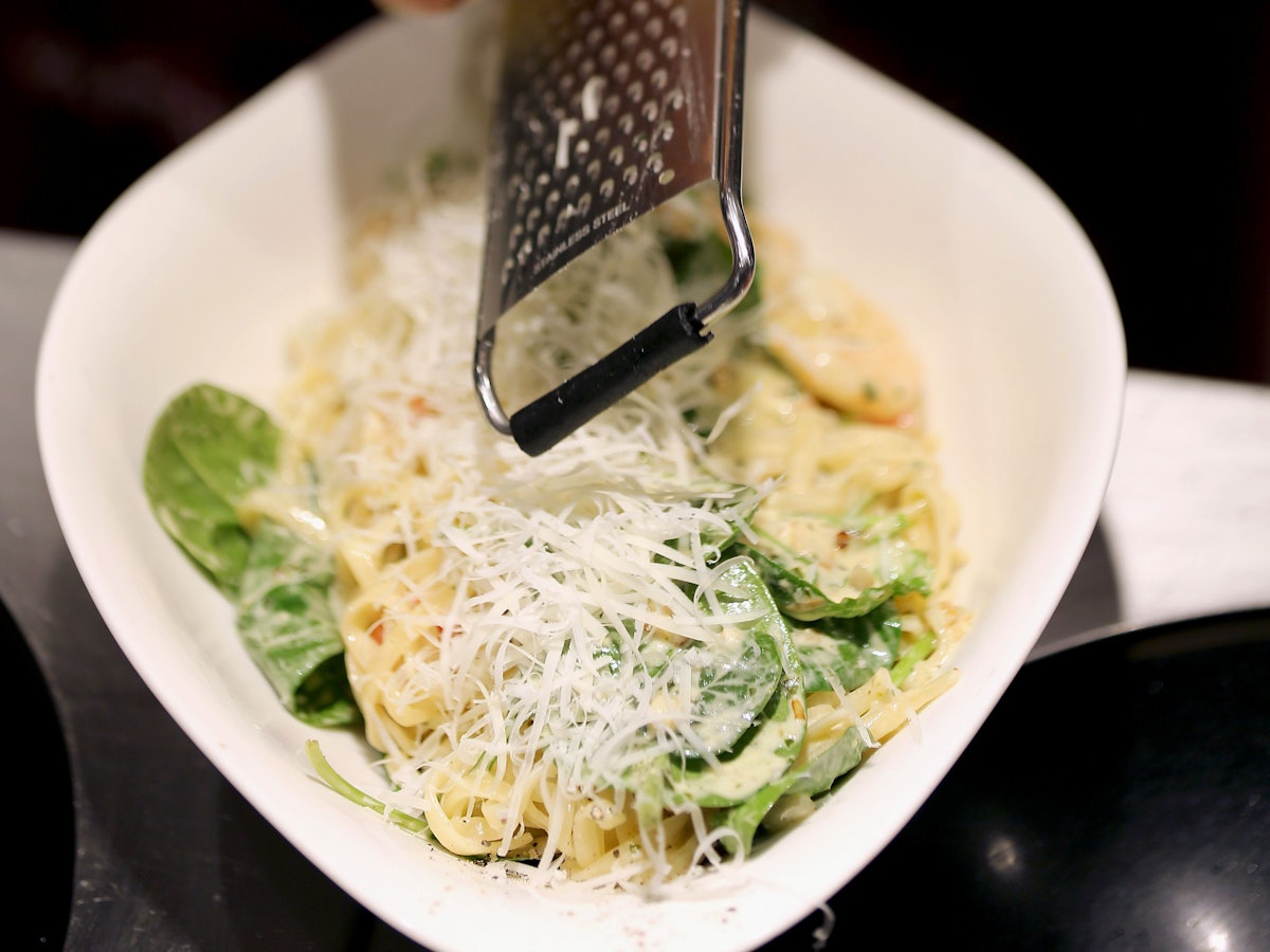 Ein Köchin reibt in einer Filiale der Restaurantkette Vapiano Parmesan auf ein Pasta-Gericht.