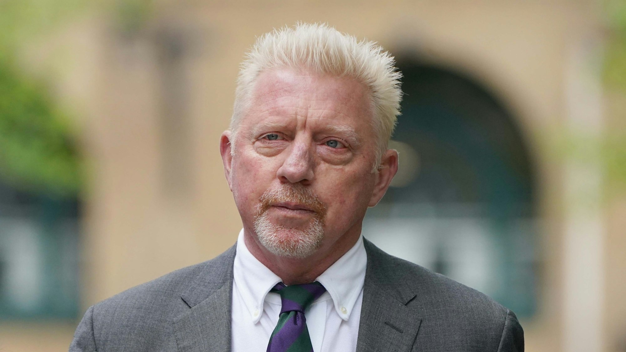 Das Foto zeigt den ehemaligen Tennis-Profi Boris Becker im Anzug vor einem Gebäude.