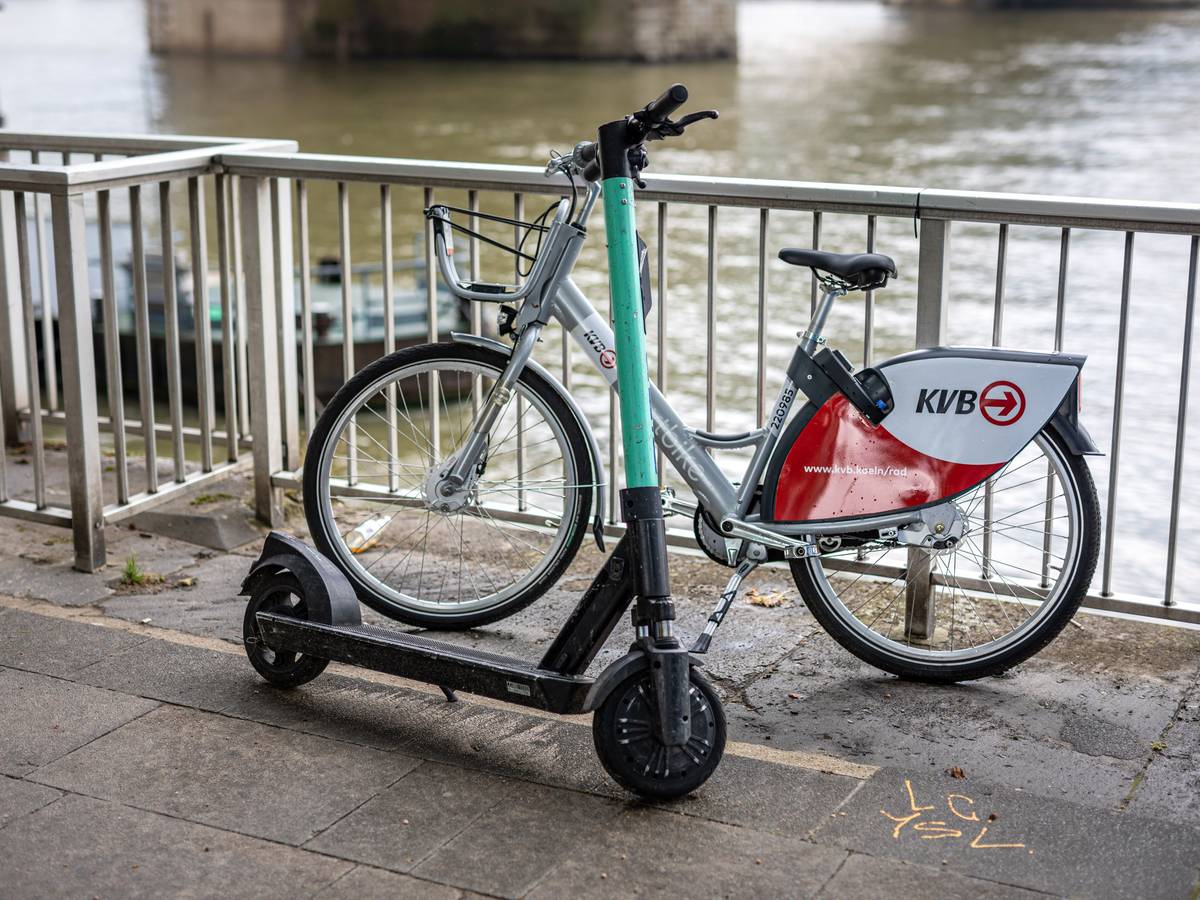 Ein E-Scooter und ein Leihfahrrad der Kölner Verkehrsbetriebe (KVB) stehen am Rheinufer vor der Hohenzollernbrücke an der Kölner Altstadt am Geländer. Die KVB arbeitet ab sofort mit dem Mobilitätsdienstleister Bolt zusammen.