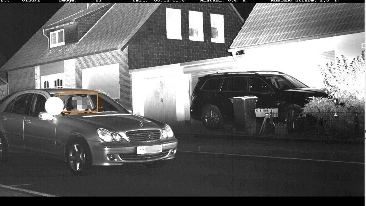 Schwarz-weiß-Foto eines Mercedes, der mit zu hoher Geschwindigkeit durch eine Ortschaft fährt.
