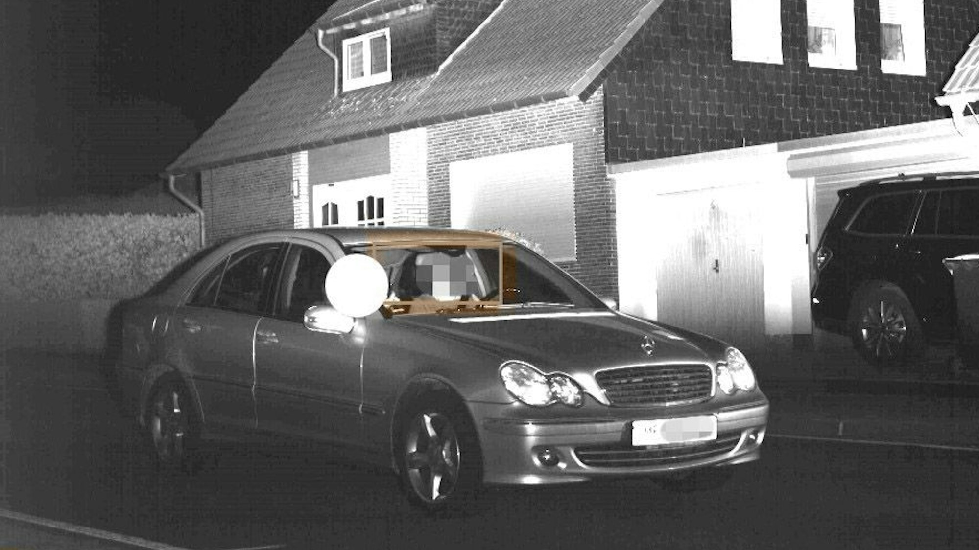 Schwarz-weiß-Foto eines Mercedes, der mit zu hoher Geschwindigkeit durch eine Ortschaft fährt.