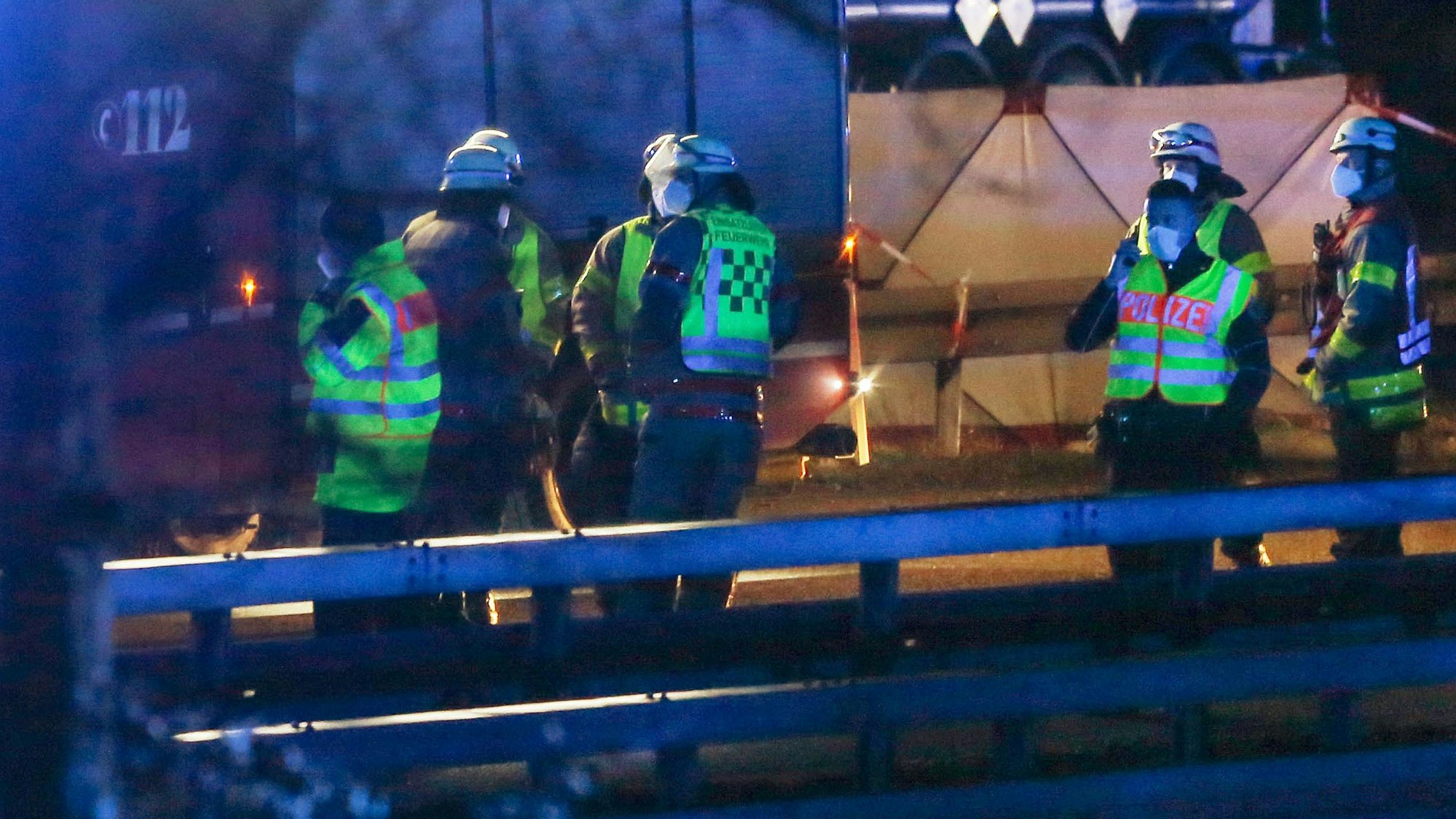 Feuerwehrleute und Polizisten stehen an der Autobahn 44 bei Aachen. Auf einem Rastplatz an der A44 ist ein 22-jähriger Belgier bei einem Unfall ums Leben gekommen.