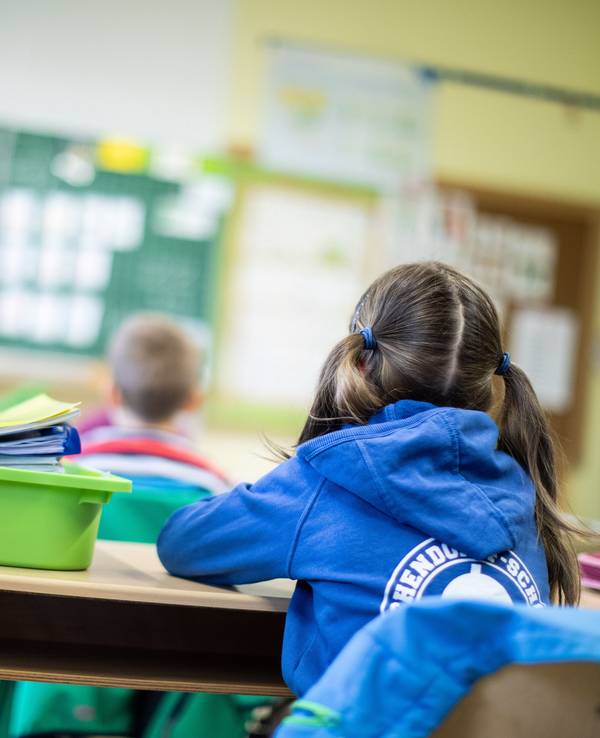 Schülerinnen und Schüler einer Grundschule sitzen mit Abstand in ihrem Klassenraum.