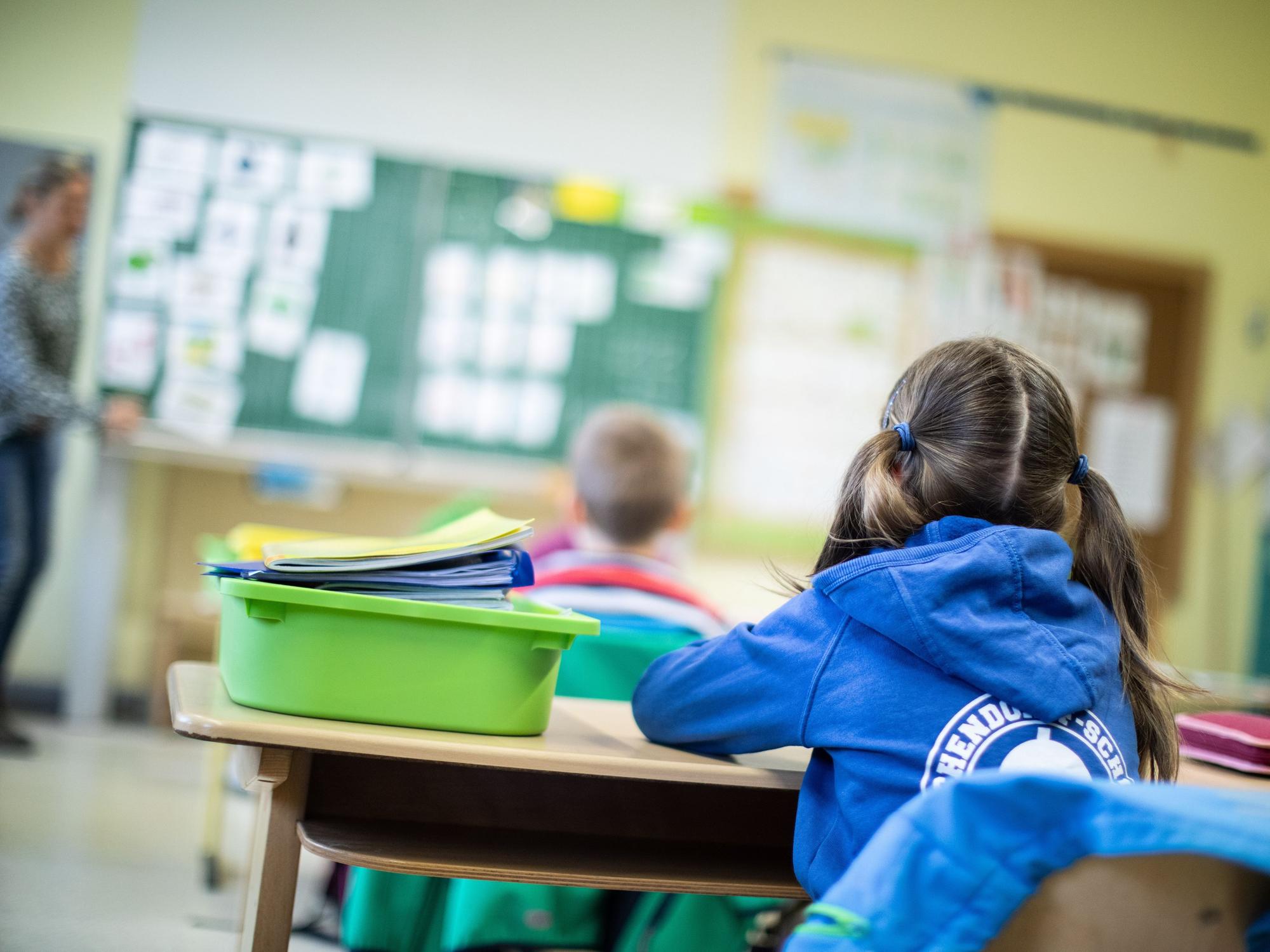 Schülerinnen und Schüler einer Grundschule sitzen mit Abstand in ihrem Klassenraum.