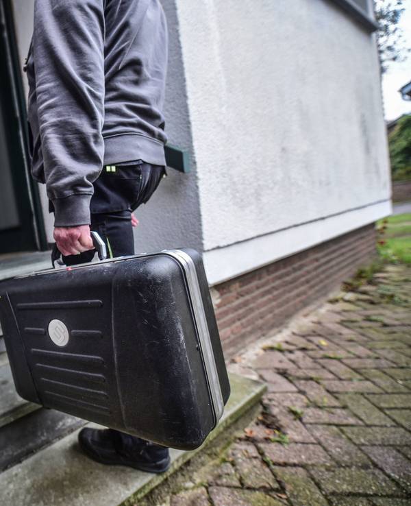 Ein Mann mit Handwerker-Koffer steht vor der geöffneten Haustür einer Frau.