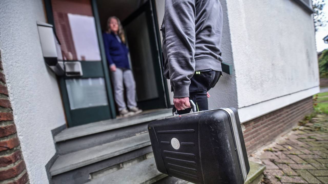 Ein Mann mit Handwerker-Koffer steht vor der geöffneten Haustür einer Frau.