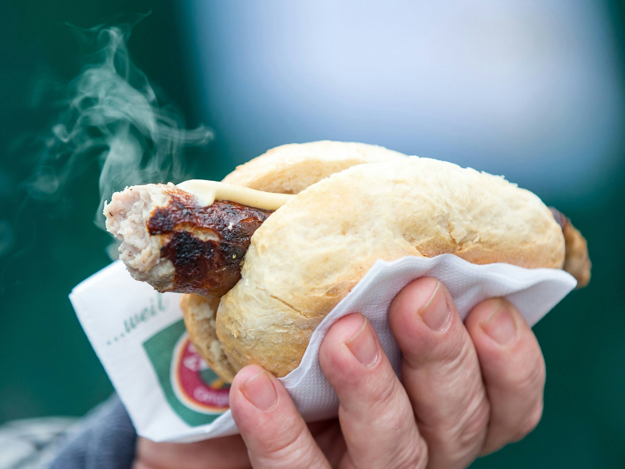 Eine originale Thüringer Rostbratwurst dampft in einem Brötchen.