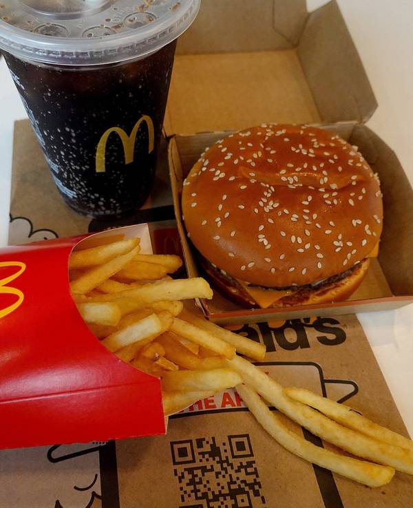 Ein Burger, eine Pommes und ein Getränk von McDonald's auf einem Tisch.