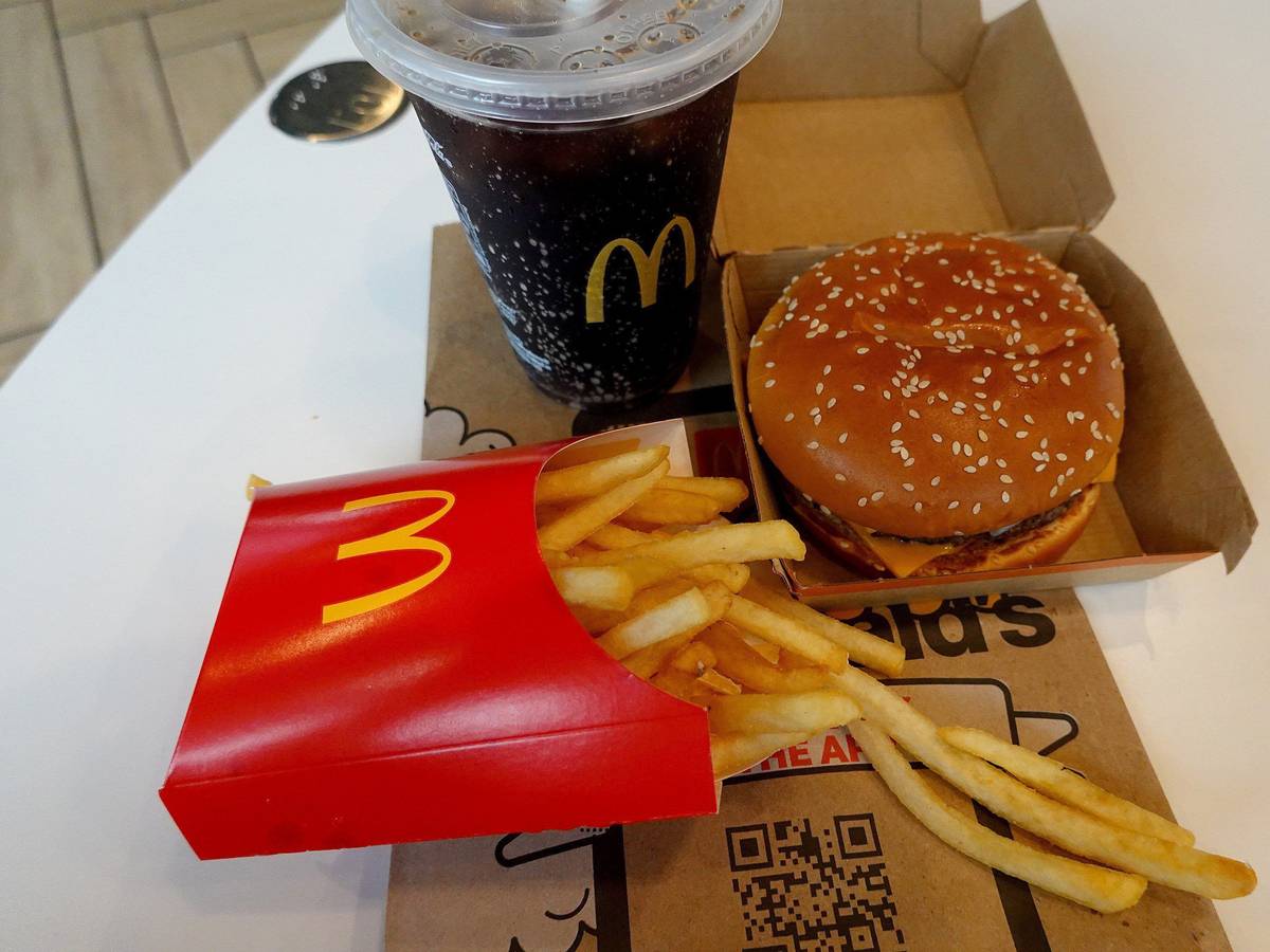 Ein Burger, eine Pommes und ein Getränk von McDonald's auf einem Tisch.