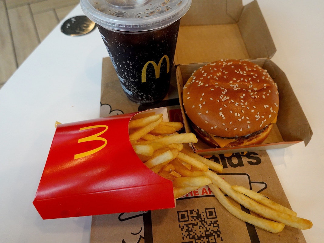 Ein Burger, eine Pommes und ein Getränk von McDonald's auf einem Tisch.
