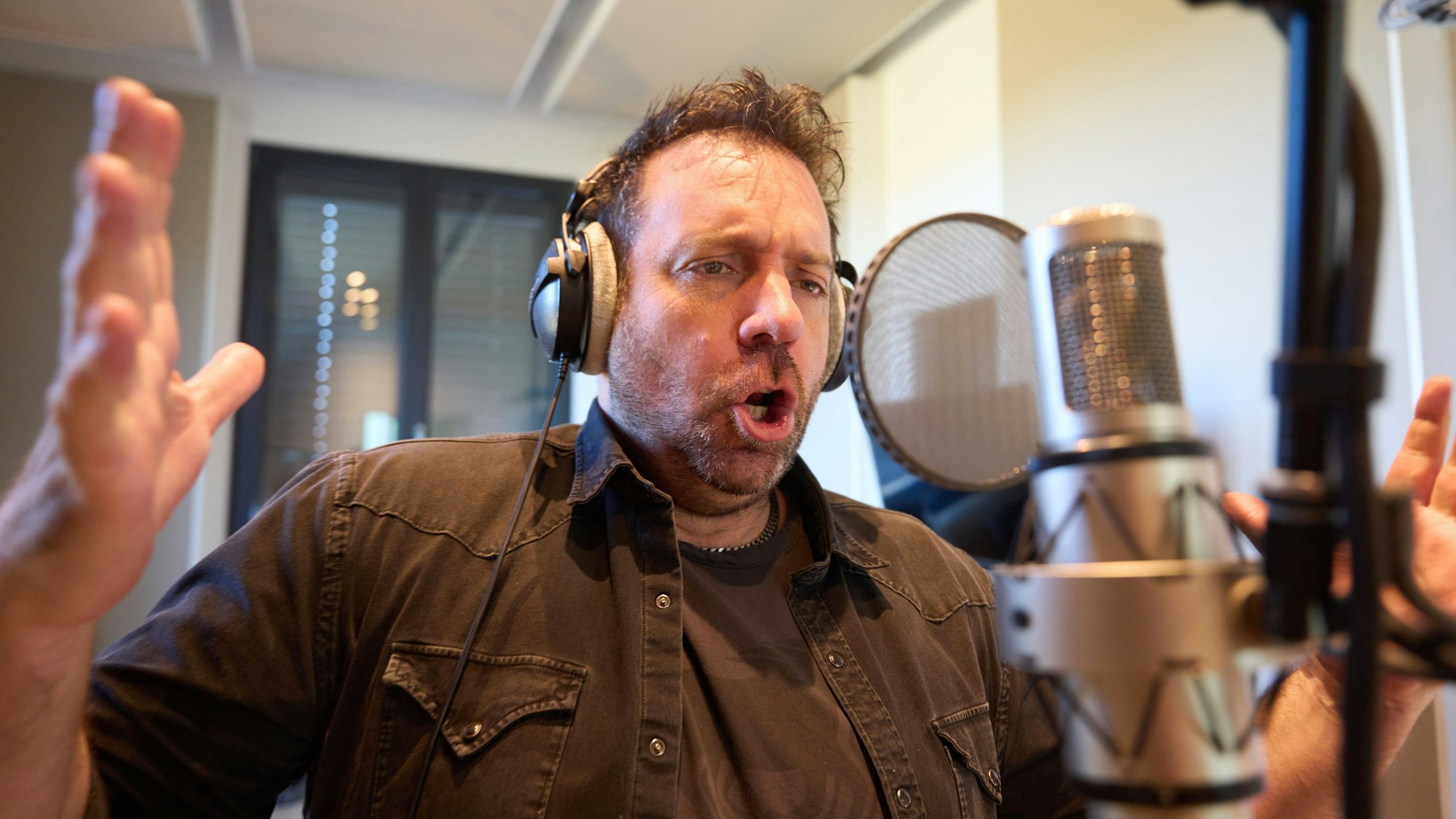 Ikke Hüftgold singt mit ausgebreiteten Armen im März 2022 in seinem Studio in Limburg.