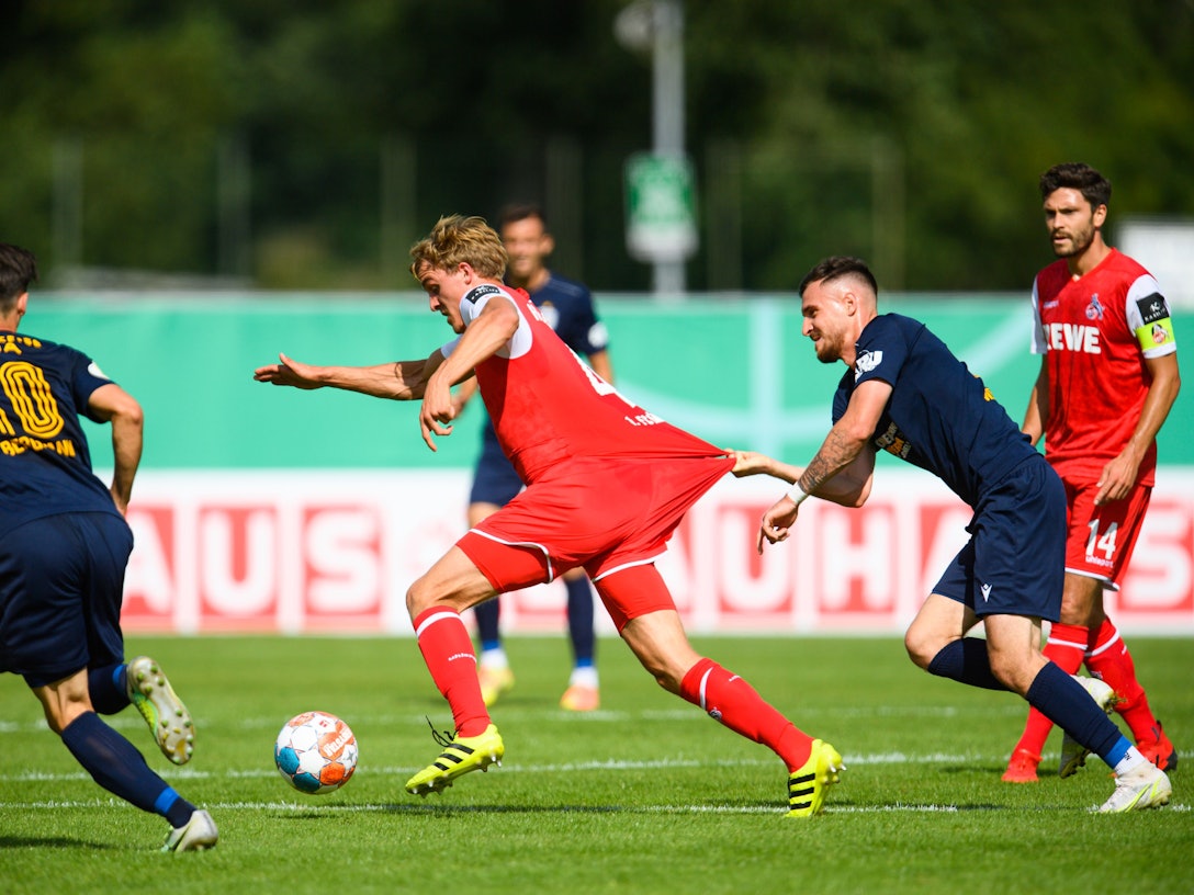 Timo Hübers wird im Spiel des 1. FC Köln im DFB-Pokal von Gegenspieler Theodor Bergmann gehalten.