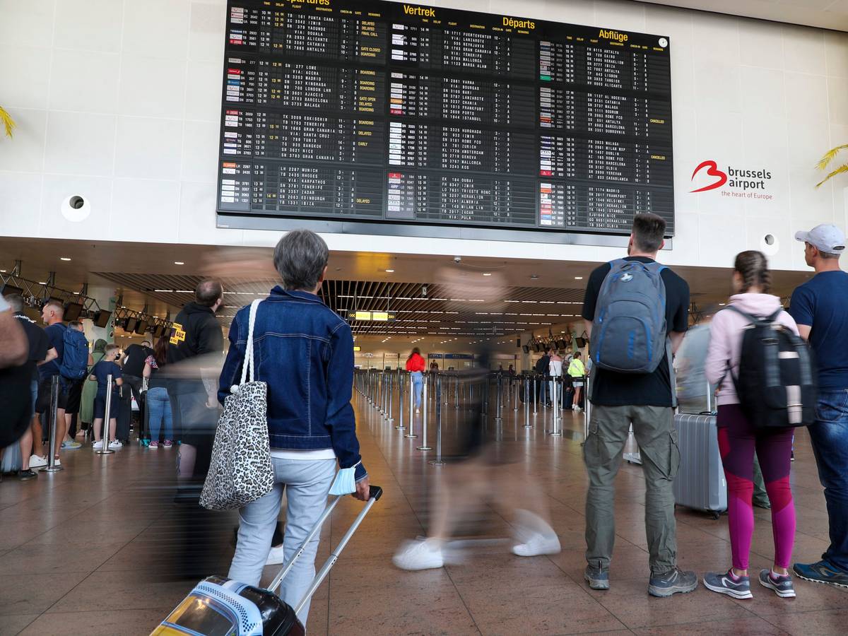 Reisende schauen in der Abflughalle des Brüsseler Flughafens in Zaventem auf die Anzeigetafel für den Abflug.