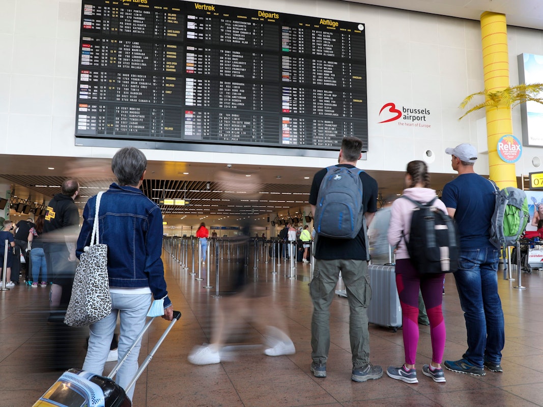 Reisende schauen in der Abflughalle des Brüsseler Flughafens in Zaventem auf die Anzeigetafel für den Abflug.