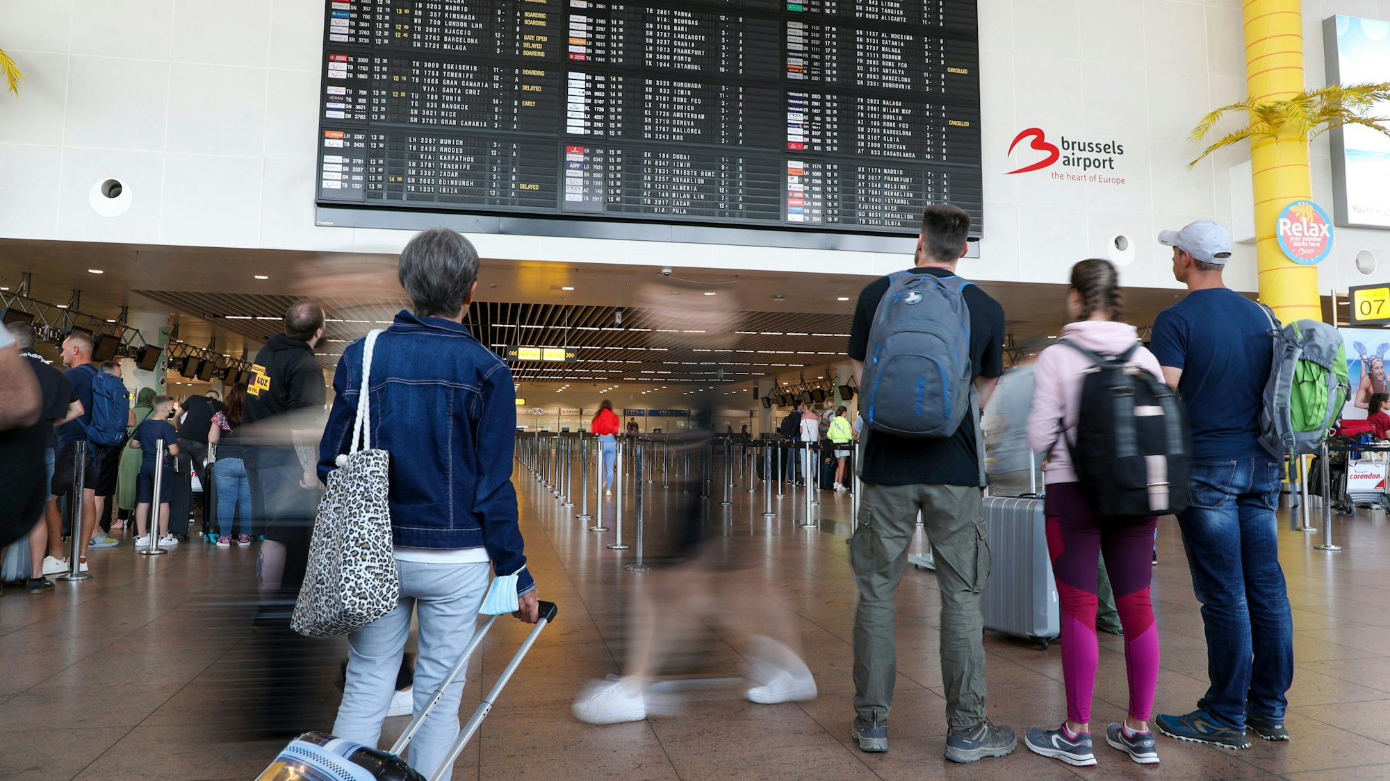 Reisende schauen in der Abflughalle des Brüsseler Flughafens in Zaventem auf die Anzeigetafel für den Abflug.