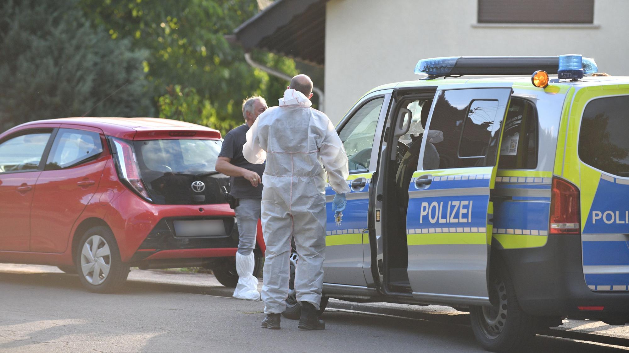 Einsatzkräfte der Polizei und Spurensicherung stehen vor einem Haus.