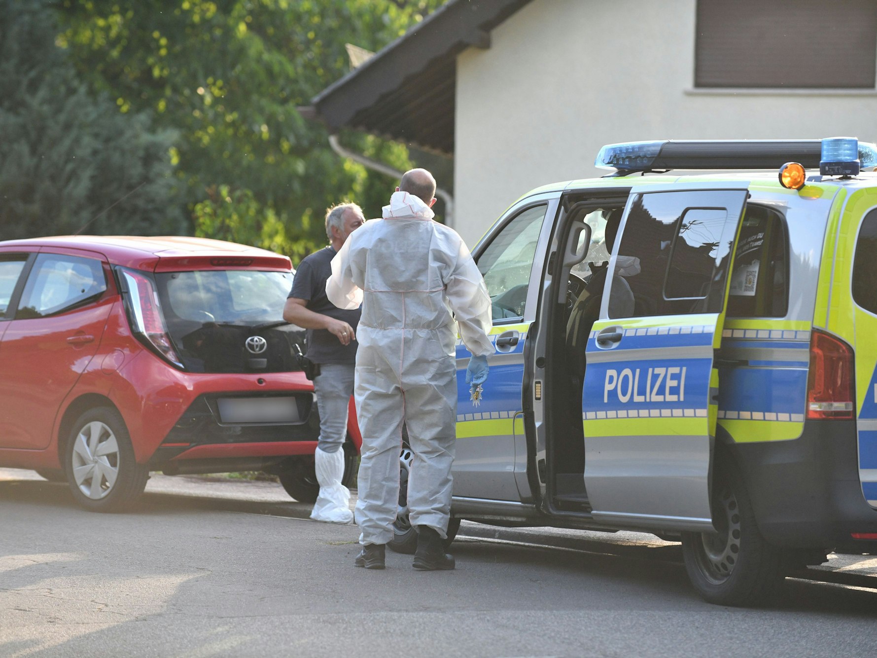 Einsatzkräfte der Polizei und Spurensicherung stehen vor einem Haus. Im Streit um eine Mietwohnung sind am Freitag im saarländischen Ottweiler zwei Menschen getötet und ein Mann verletzt worden.