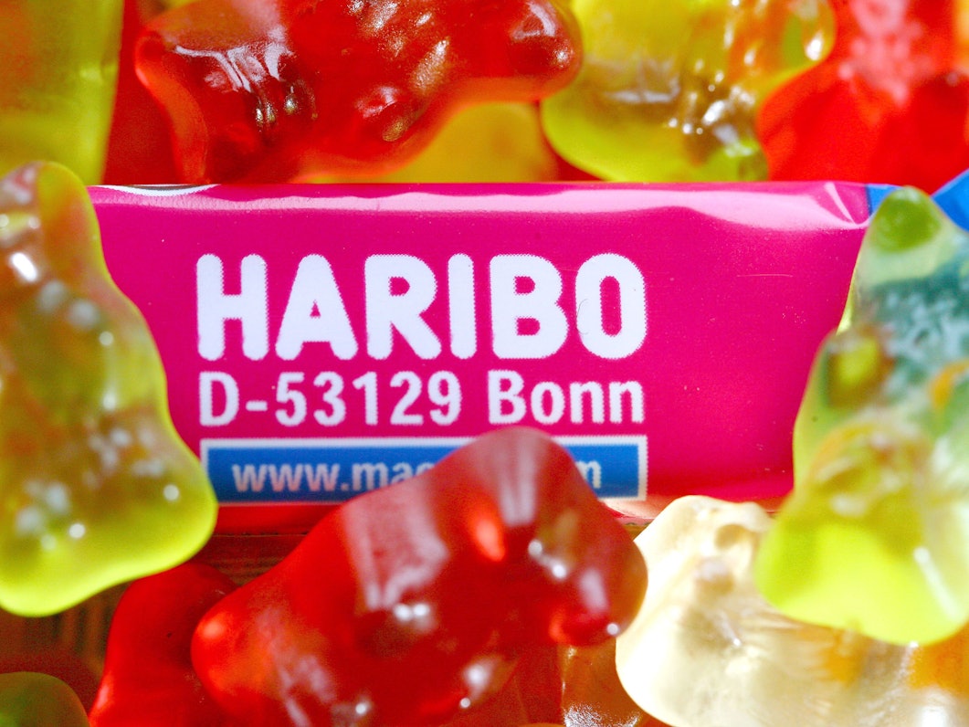 Die Nahaufnahme zeigt eine Tüte „Maoam“ mit dem Schriftzug „D-53129 Bonn“ und viele Gummibärchen der Firma Haribo.