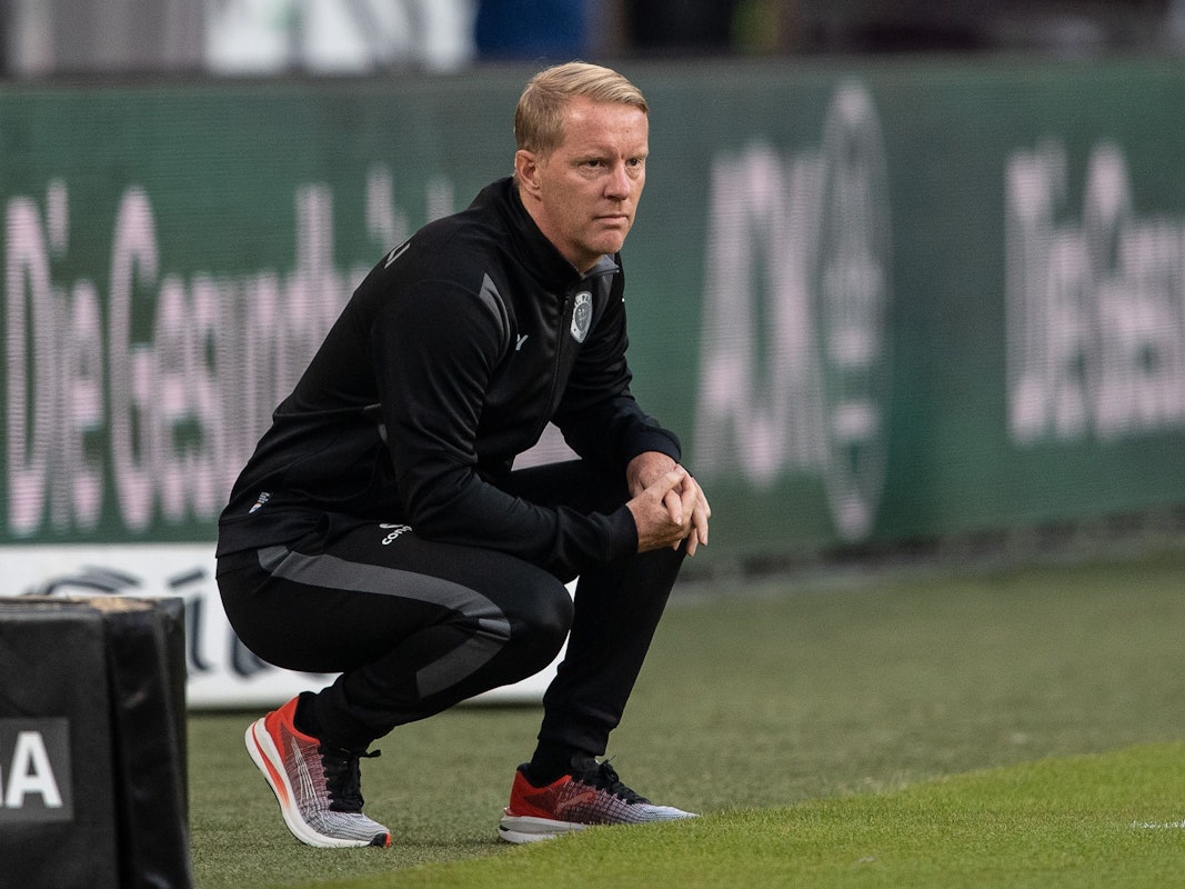Timo Schultz geht bei einem Spiel des FC St. Pauli in seiner Coachingzone in die Hocke.