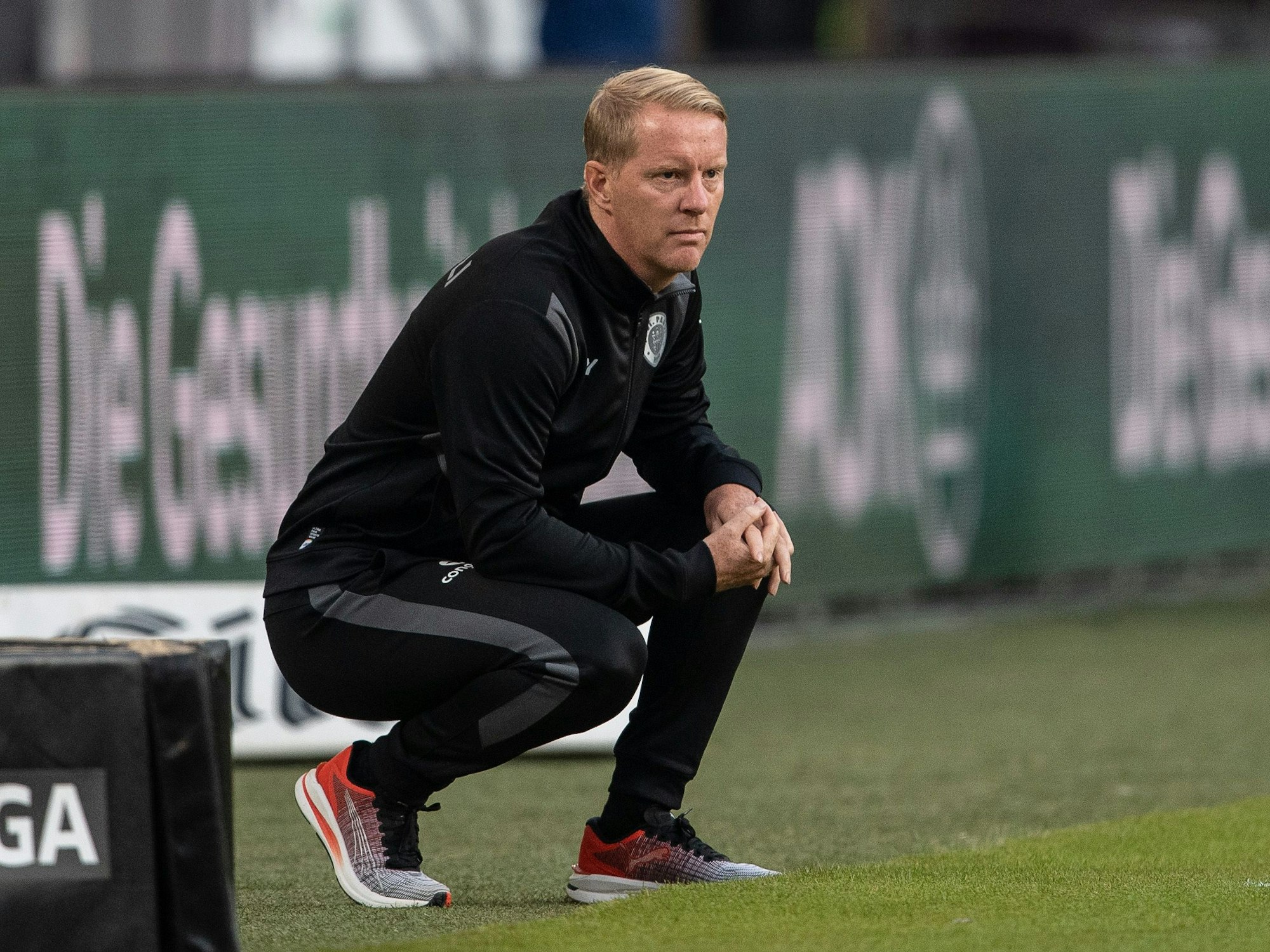 Timo Schultz geht bei einem Spiel des FC St. Pauli in seiner Coachingzone in die Hocke.