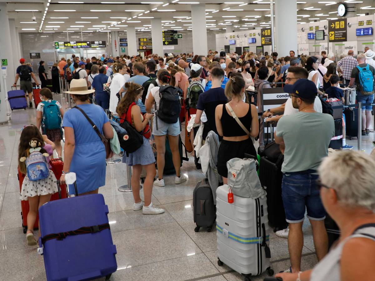 Reisende warten am Flughafen Palma de Mallorca an der Gepäckaufgabe.