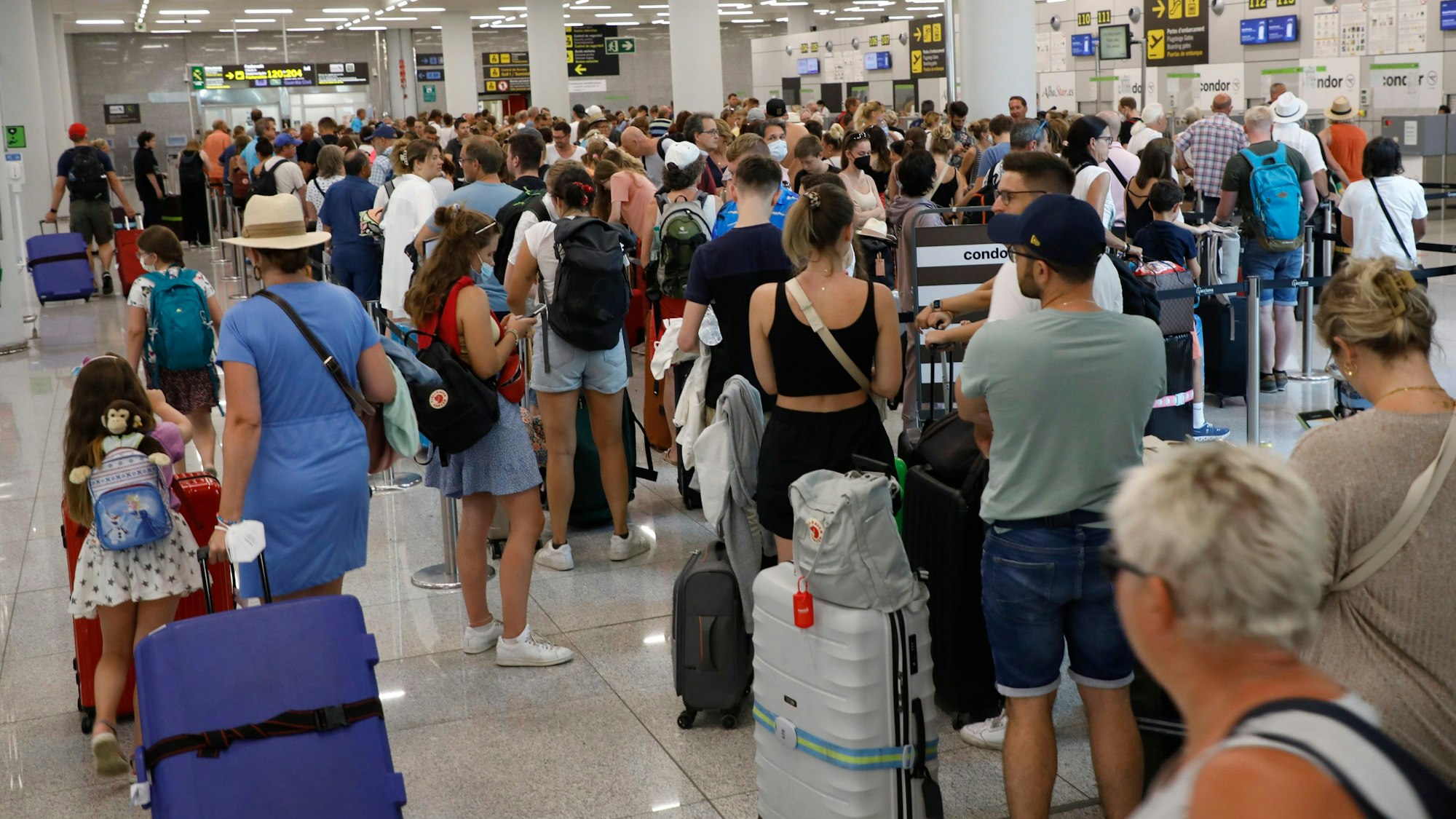 Reisende warten am Flughafen Palma de Mallorca an der Gepäckaufgabe.
