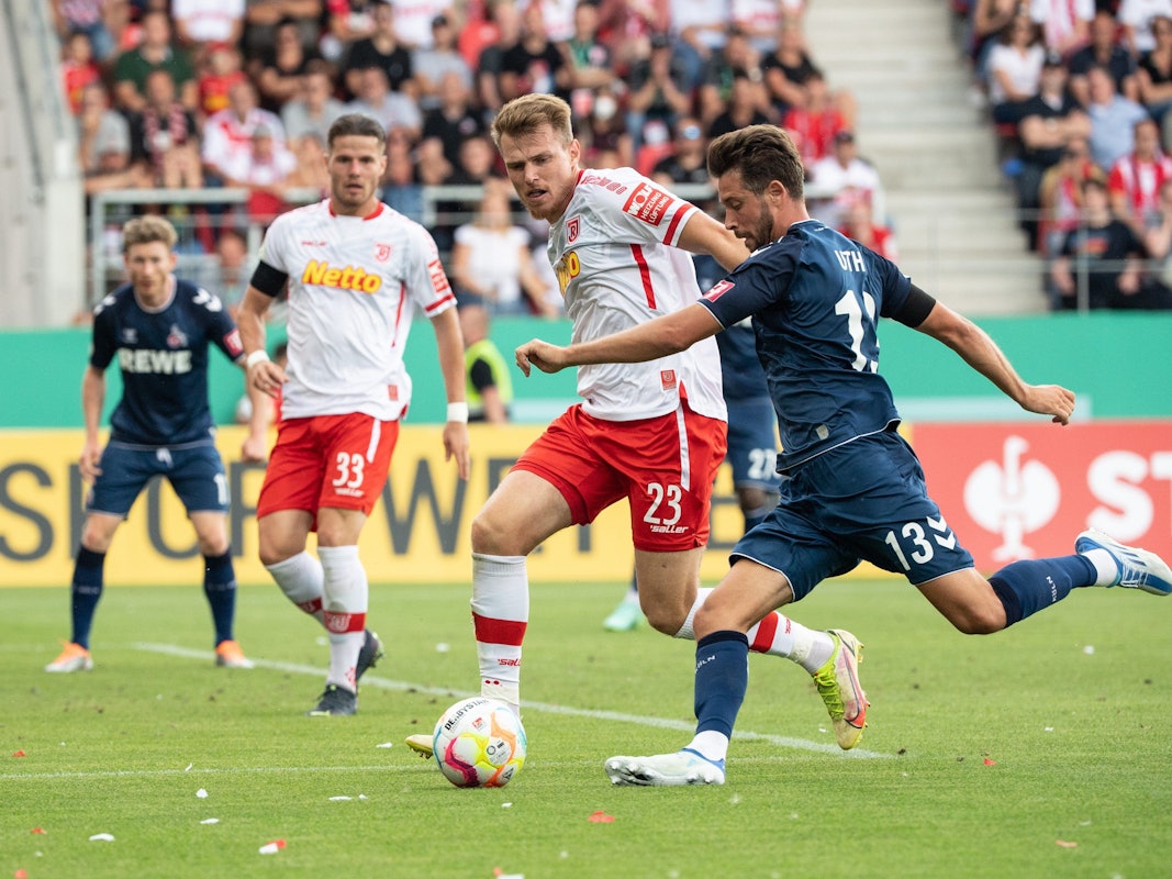 Steve Breitkreuz vom SSV Jahn Regensburg (l) und Mark Uth vom 1. FC Köln im Zweikampf um den Ball.