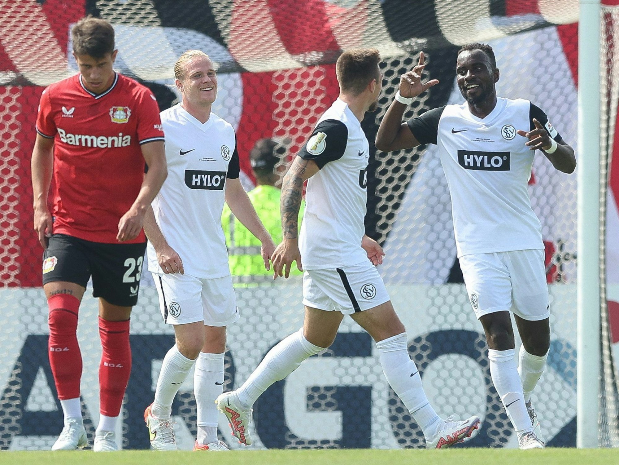 Adam Hlozek geht enttäuscht davon, während die Spieler des SV Elversberg im Hintergrund jubeln.