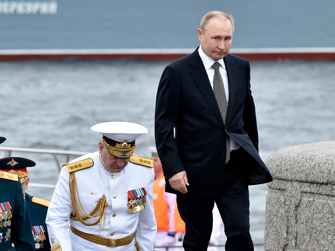Russia's President Vladimir Putin (R) walks with Commander-in-Chief of the Russian Navy, Admiral Nikolai Yevmenov (C) as he takes part in the main naval parade marking Russian Navy Day, in St. Petersburg on July 31, 2022. (Photo by Olga MALTSEVA / AFP)