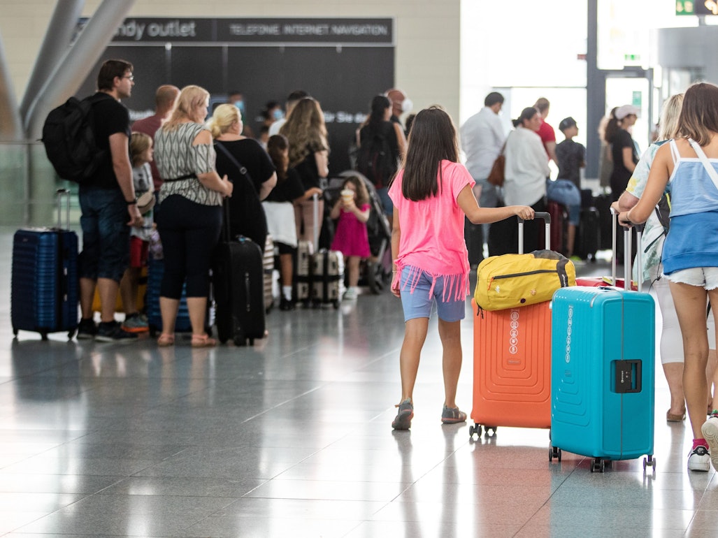 Fluggäste gehen mit ihrem Gepäck durch ein Terminal des Flughafens.
