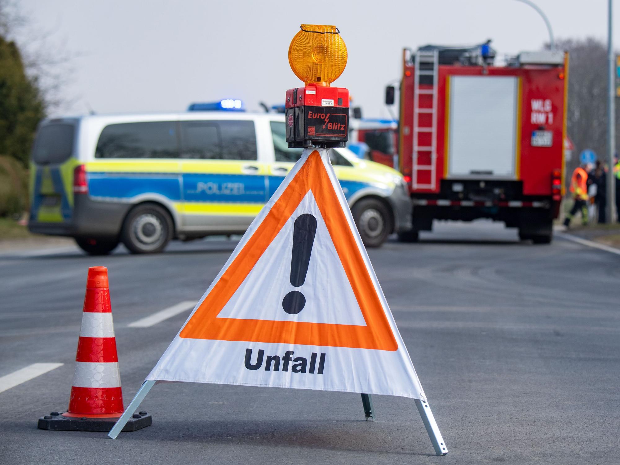 Ein Schild mit der Aufschrift Unfall sowie ein Polizei- und Feuerwehrfahrzeug stehen nach einem Unfall auf der Insel Usedom auf der Straße.